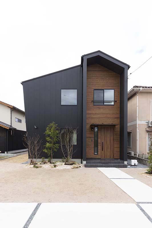 黒いガルバリムの外壁と木目のアクセント