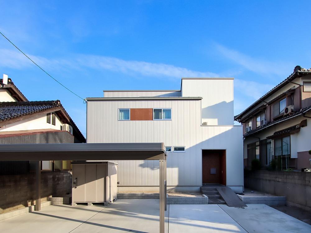 白とグレーのスタイリッシュな外観。窓の横の木目がポイント。